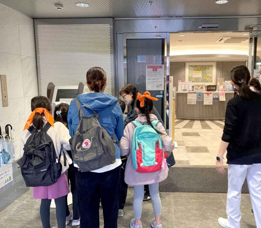 東京国際大堀病院の入り口で消毒をする三鷹市立第四小学校の生徒たち